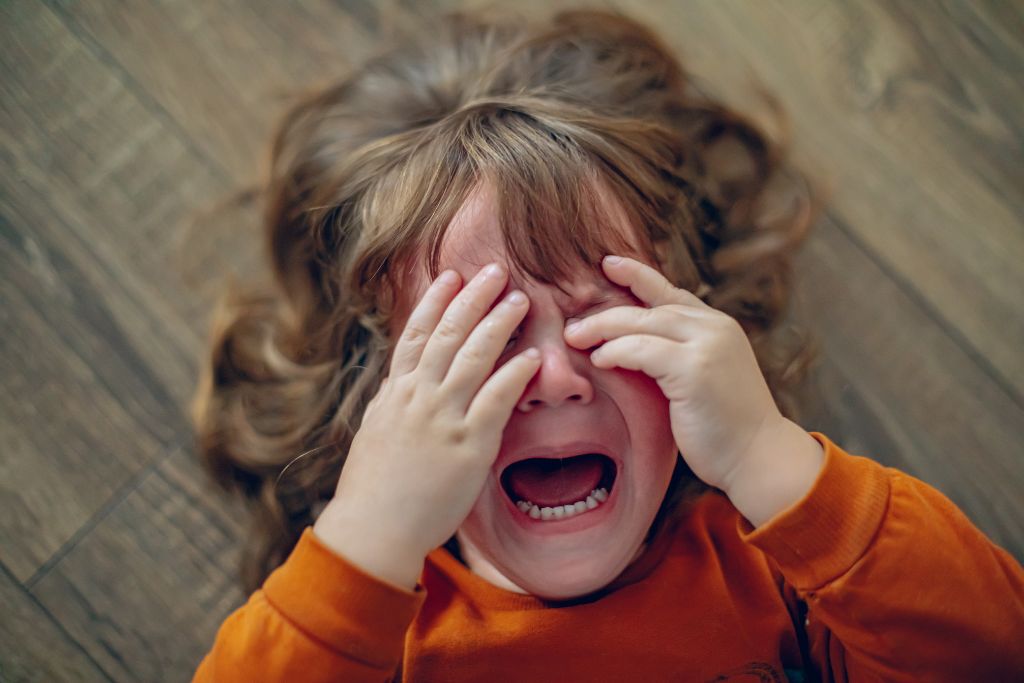 Girl crying and laying on the floor. photo for the blog post: How to help your child settle during big emotions