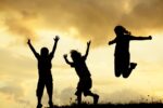 Children jumping on a field during sunset