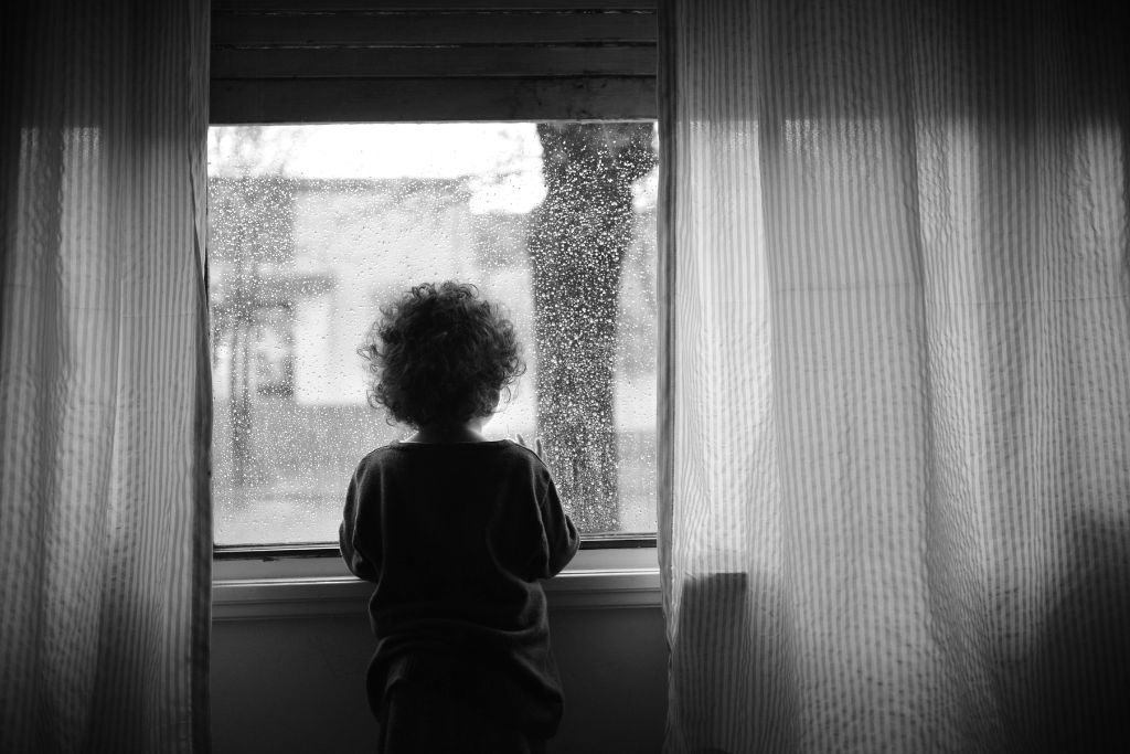 Child looking out the window in black and white photo